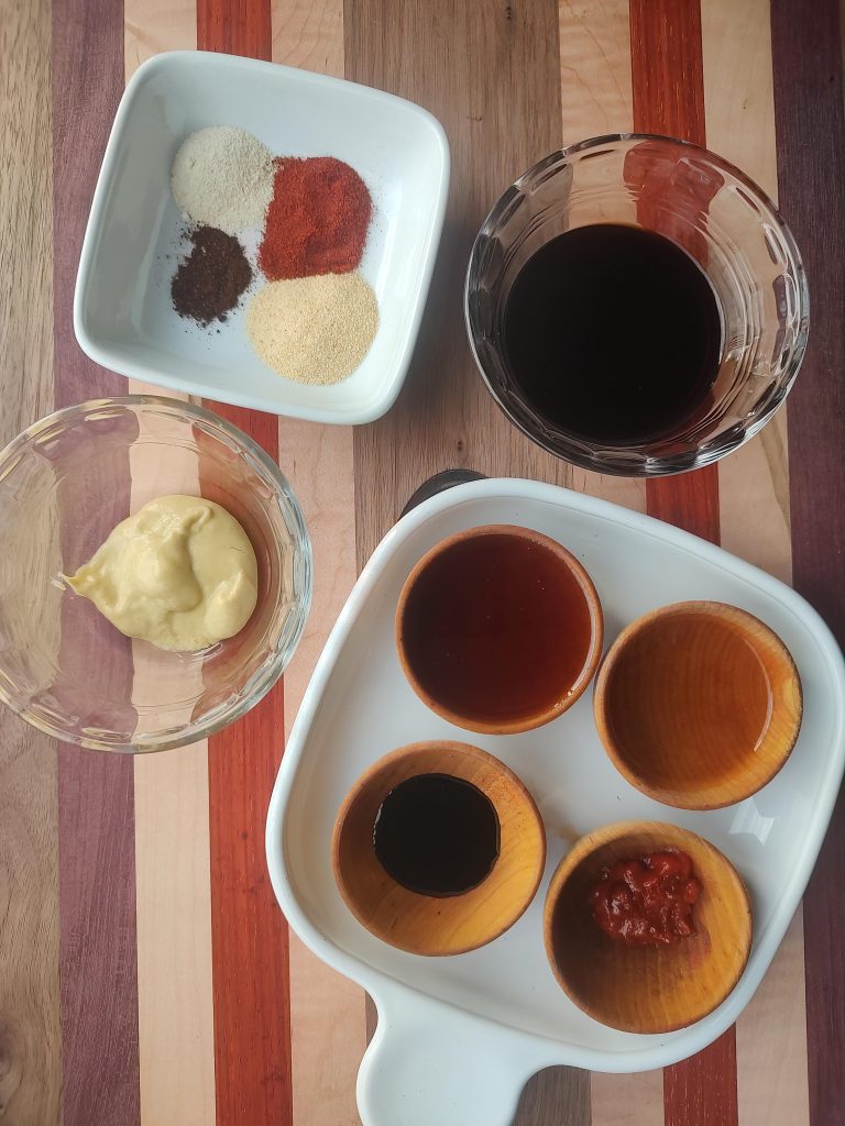 Seasonings and spices in small bowls on a wooden cutting board